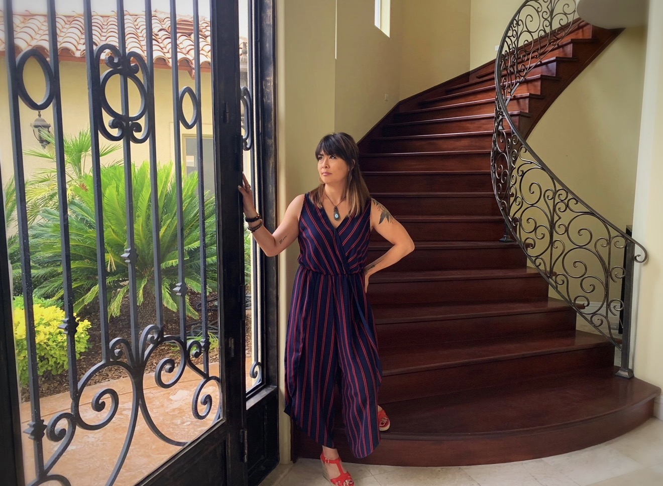 Ikumi in a striped jumpsuit beside a curved wooden staircase